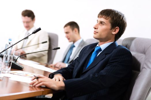 Portrait of a businessman, said into the microphone, in the background colleagues communicate with each other