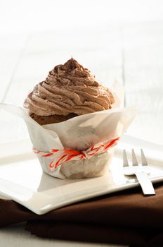 A chocolate cupcake on white plate and fork