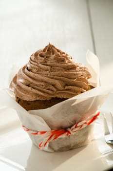 A chocolate cupcake on white plate and fork