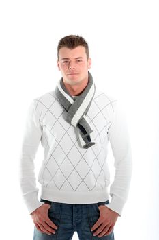 Cool handsome macho man in a stylish winter scarf and jersey standing with his thumbs hooked into the pockets of his jeans isolated on white
