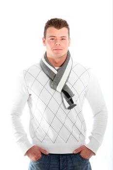 Handsome fashionable man in a winter outfit with a trendy scarf standing facing the camera with his hands in his pockets isolated on white