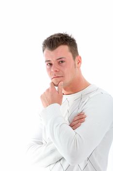 Serious young man deep in thought standing sieways with his hand to his chin looking at the camera isolated on white