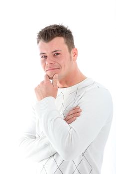 Thoughtful handsome young man with an amused smile standing at an angle looking at the camera with his hand to his chin isolated on white