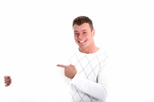 Enthusiastic handsome man with a beaming smile pointing with his finger to a blank placard that he is holding to the side at chest height isolated on whte