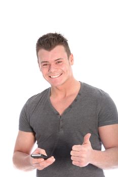 Smiling handsome young man holding a mobile phone in one hand giving a thumbs up of approval and success at news he has just received isolated on white