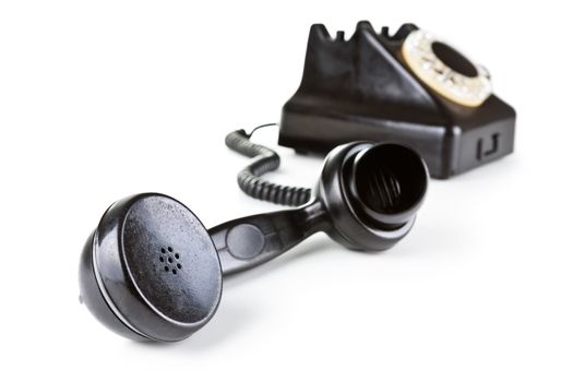 Old black telephone with rotary dial. Focus on handset in foreground. Isolated on white