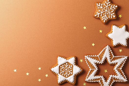 Christmas gingerbreads with golden stars on brown paper background. Top view