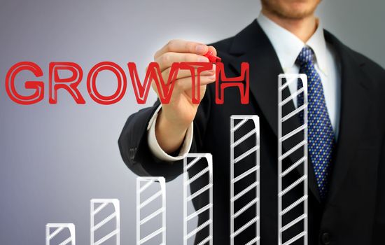 Businessman writing growth over a rising bar graph