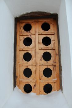 Ancient wooden window with a unusual pattern in a wall