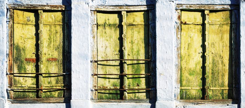 Three old windows with wooden shutters, background