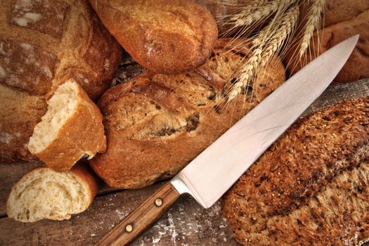 A selection of bread loaves with knife on wood table