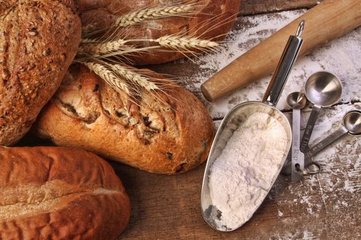 Assortment of loaves of bread with flour on wood table