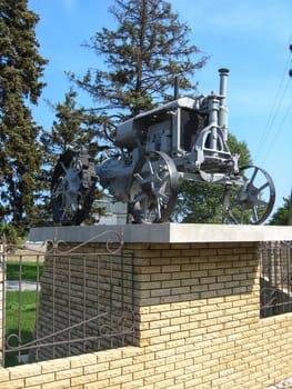 The ancient retro tractor standing on a pedestal