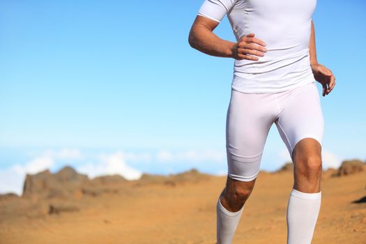 Sport fitness runner running outside in nature. Man training trail running for marathon run. Unrecognizable fit male athlete working out.
