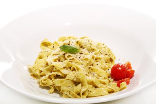 Italian pasta with basil and tomatoes on a plate isolated on white background