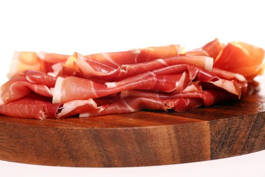 Proscuitto on a wooden plate isolated on white background