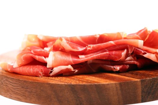 Proscuitto on a wooden plate isolated on white background