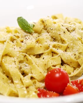 Italian pasta with basil and tomatoes on a plate isolated on white background