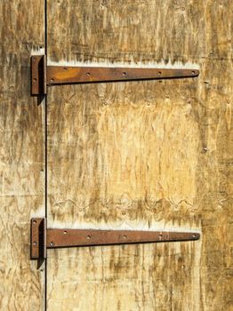 Two rusty hinges on an old wooden door