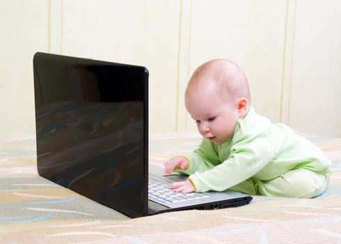 cute little girl with lies on the floor with a laptop