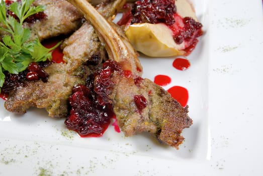 Italian kitchen.meat lamb on rib with cowberries by sauce