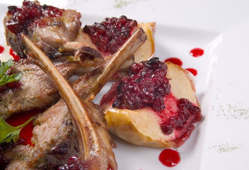 Italian kitchen.meat lamb on rib with cowberries by sauce