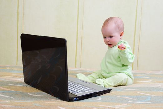 cute little girl with lies on the floor with a laptop