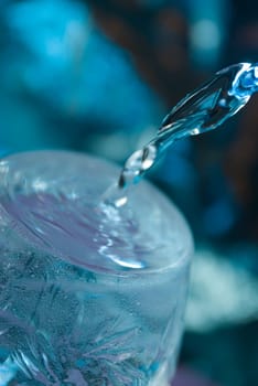 Bottle with creative splashing water.Macro of water poured into a glass 