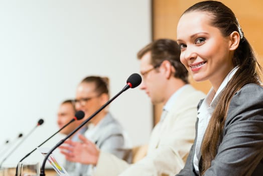 group of business people sitting at the tables at the presentation, woman looking at the camera