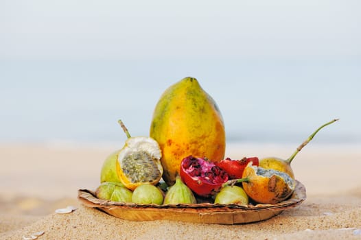 Exotic tropical fruit on the leaves plate, on the sandy beach