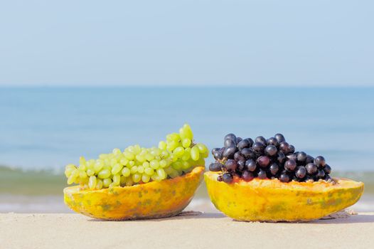 Tropical papaya and grape on the sandy shore