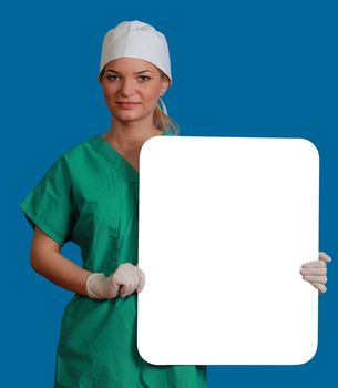 A young woman doctor holding an empty white bill board against a blue background.