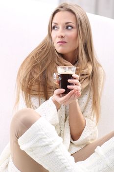 Long-haired blonde with a cup of coffee sitting on a sofa
