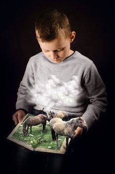 Child looks at a book and imagine a scene from nature