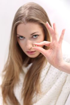 Young long-haired blonde sitting on a sofa. She holds a pill