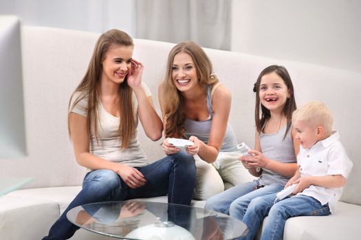 Smiling family playing video games while sitting on the sofa