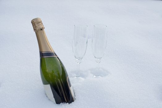 bottle of champagne and two glasses in the snow