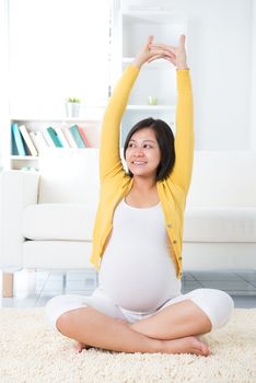 Maternity health concept. Asian pregnant woman stretching at home.
