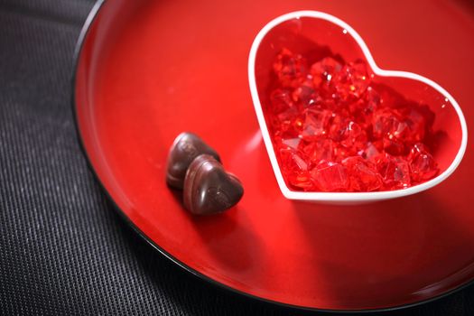 Red glass heart on a plate with chocolate