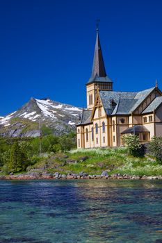 Picturesque Lofoten cathedral on Lofoten islands in Norway with snowy peaks in the background