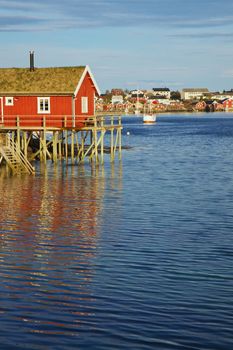 Traditional red rorbu fishing hut with sod roof in town of Reine on Lofoten islands in Norway