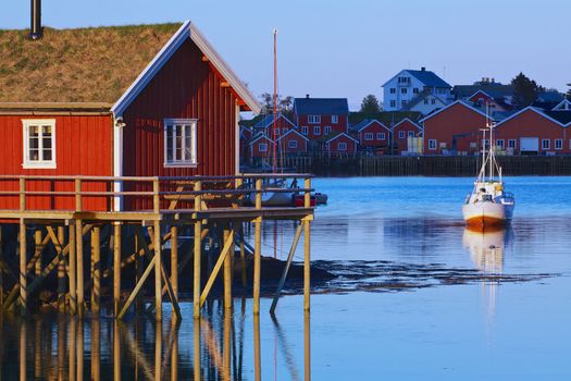 Typical red rorbu hut with sod roof lit by midnight sun in town of Reine on Lofoten islands in Norway