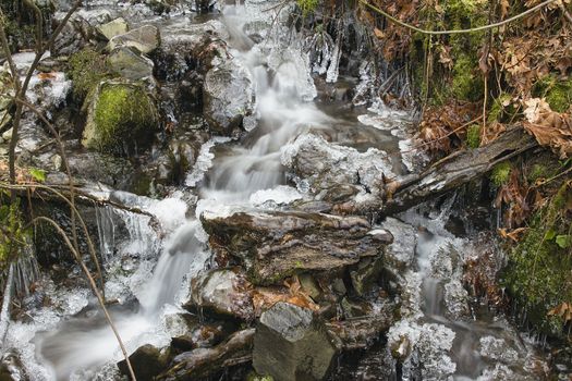 Small Stream with Water Flowing and Icicles Formation in Winter