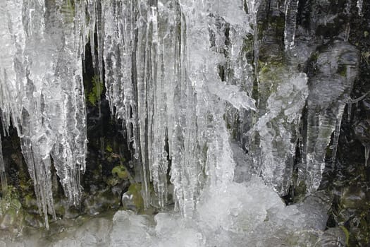 Icicles Formation on Side of Mountain Cave Rocks in Winter Background