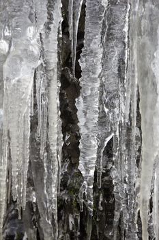 Icicles on Side of Mountain Cave Rocks in Winter Background