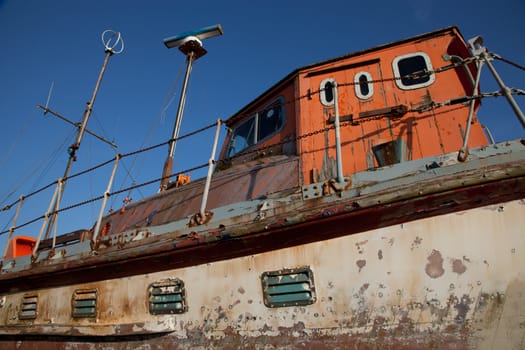 The wheelhouse and hull of an old boat with vents and flaking paint.