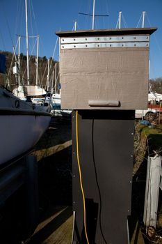 A protective box covering an electrical supply in a marina with a yellow cable.