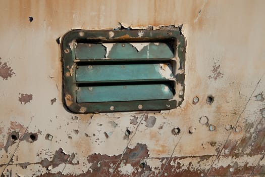 A vintage marine brass vent cover on the hull of a boat with flaky old paint.