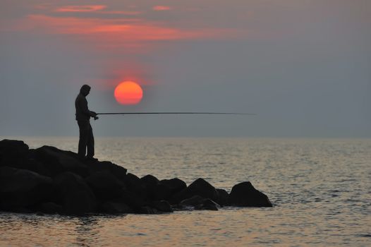 The fisherman at sunset is waiting for fish to bite