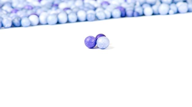 One blue and two violet little pearls isolated on background of other pearls.